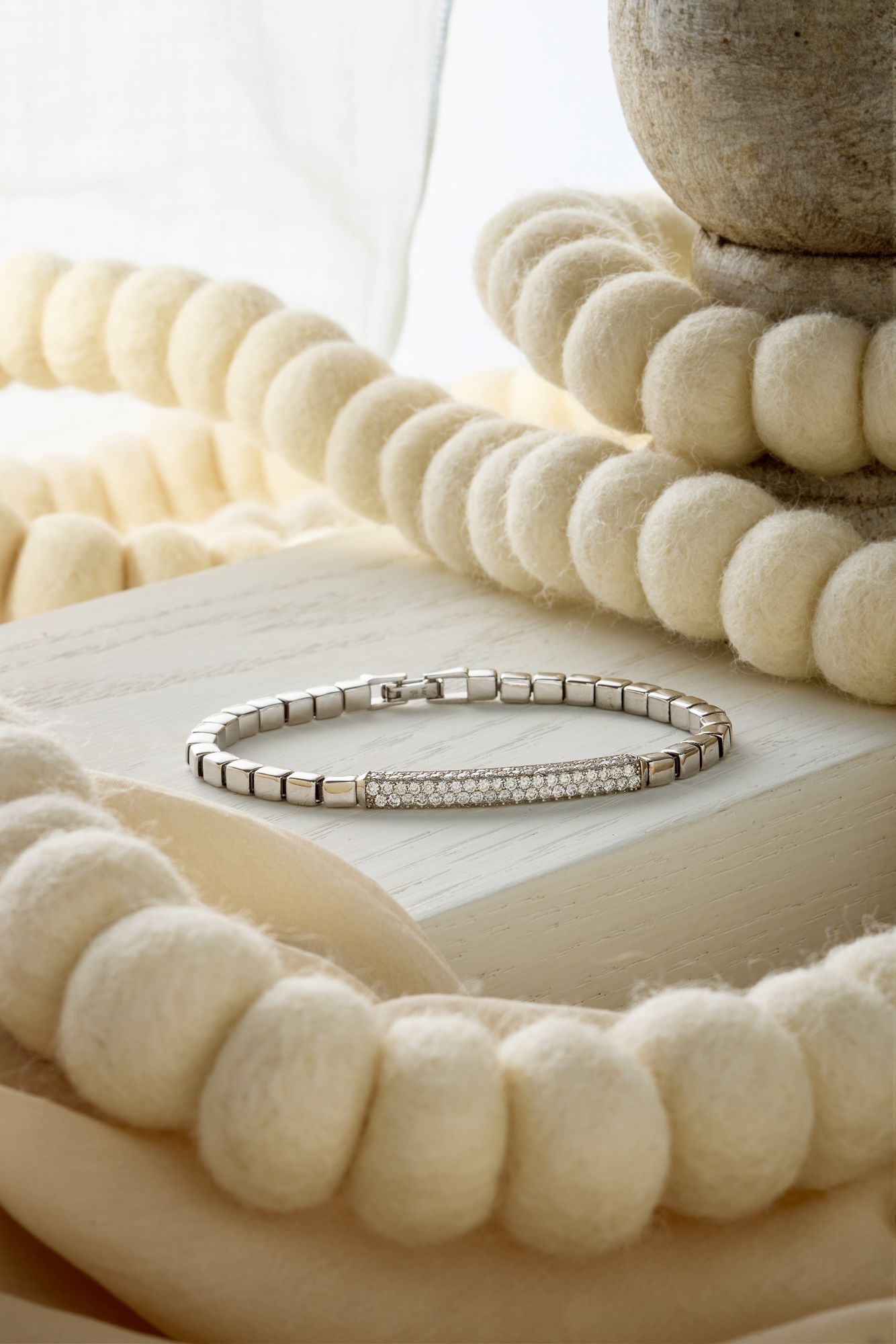 A diamond bangle resting against a strand of cream beads