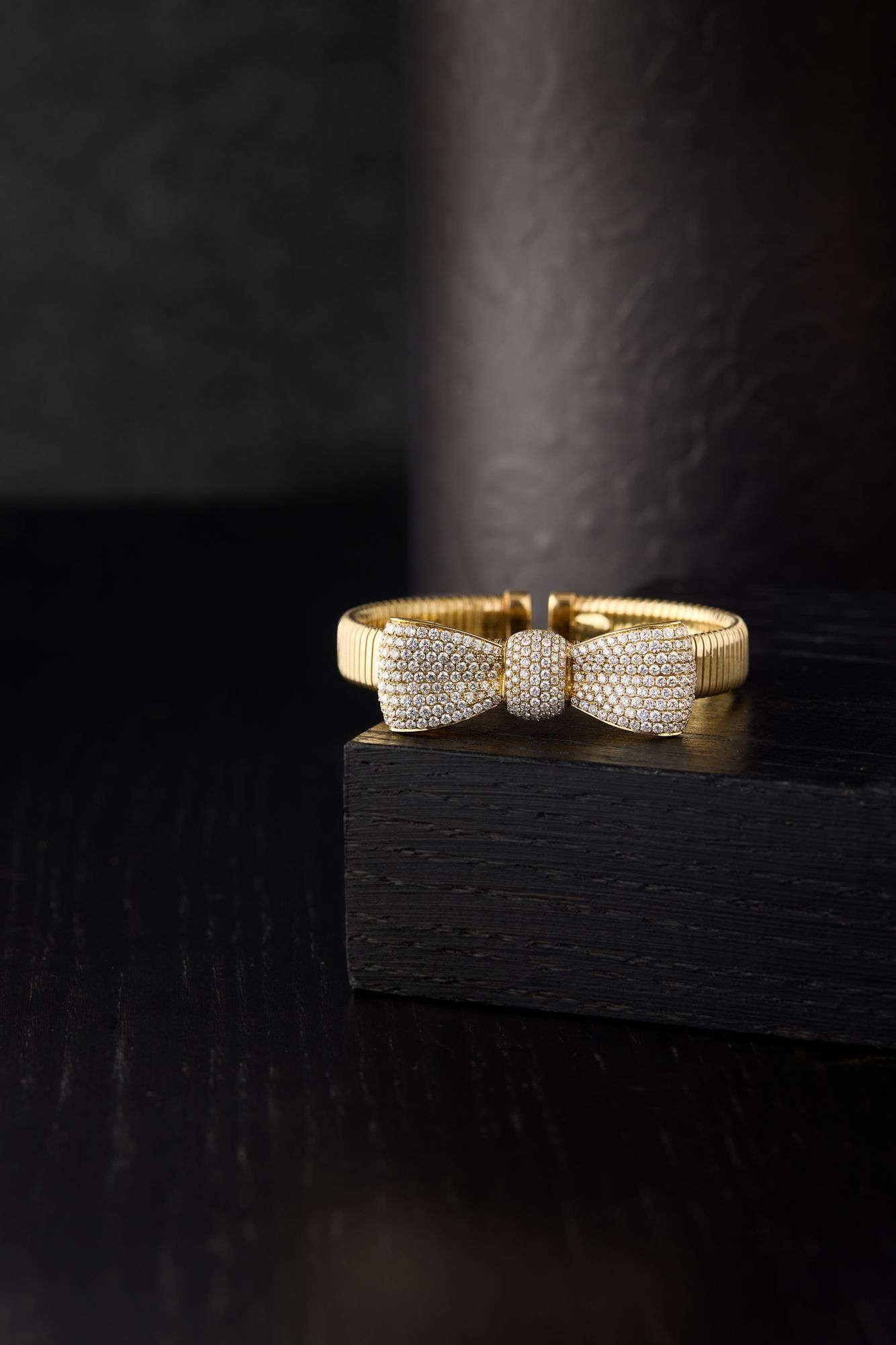 A gold and diamond ring on a dark wooden block