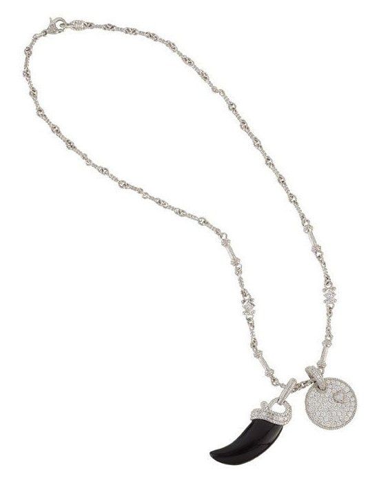 A silver chain hung with a black horn charm and an engraved disc