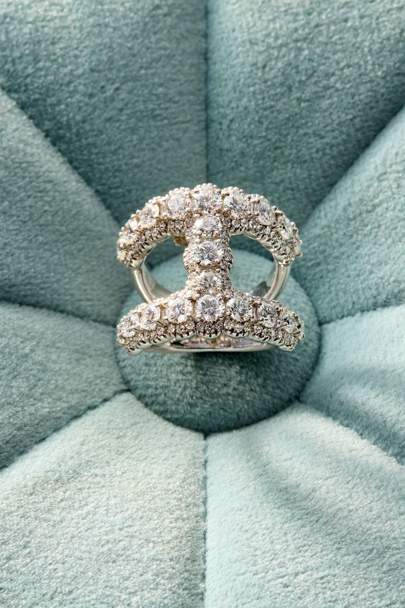 A diamond engagement ring on a pale green velvet cushion