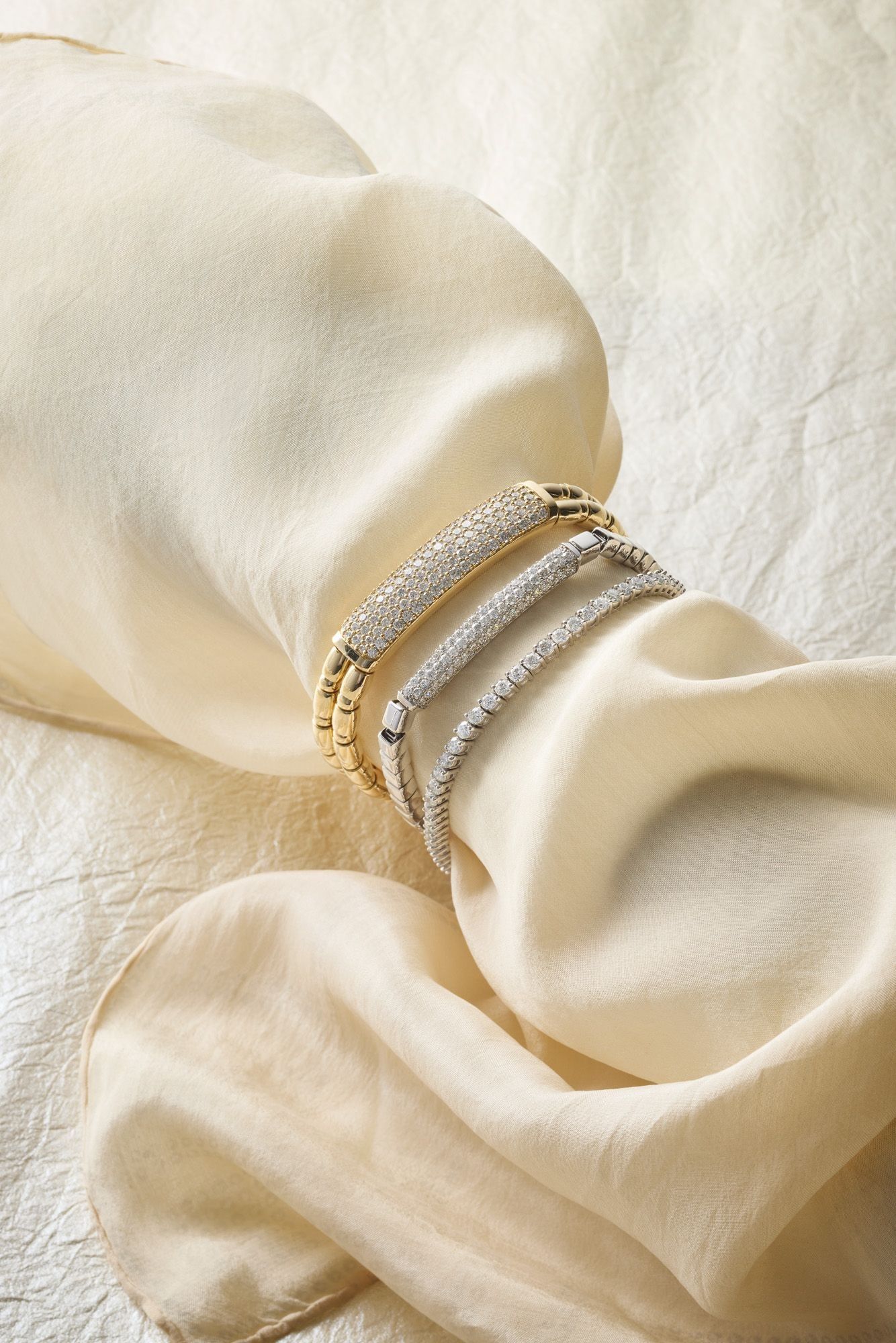 Diamond bangles resting on cream silk